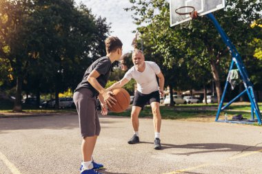 Olgun bir adam oğluyla basketbol oynuyor.