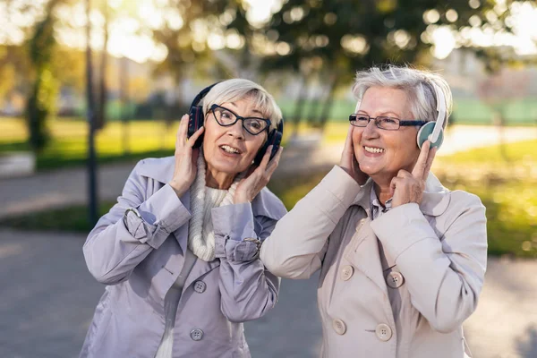 Starsze Przyjaciółki Słuchające Muzyki Naturze Kobiety Słuchające Muzyki Słuchawkami Bezprzewodowymi — Zdjęcie stockowe