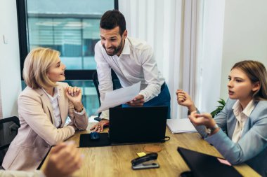 Office colleagues having discussion during meeting in conference room. Group of men and women sitting in conference room and smiling.