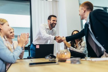 Business people shaking hands in the office. Group of business persons in business meeting. 