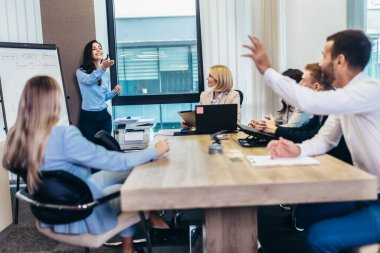 Businessman raising her hand to ask the question on a seminar in board room.