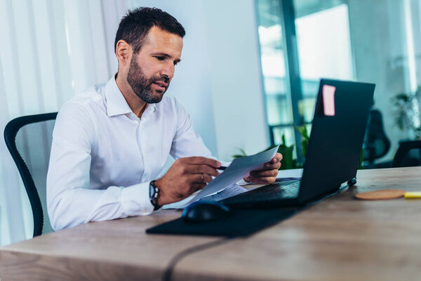 Portrait of young business man sitting at his desk in the office using laptop