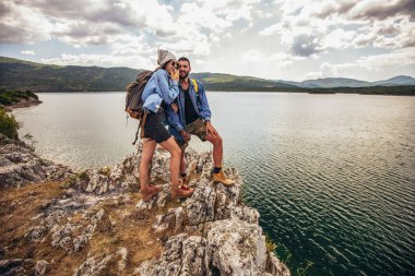 Sırt çantalı yürüyüşçüler dağ gölünün keyfini çıkarıyorlar.