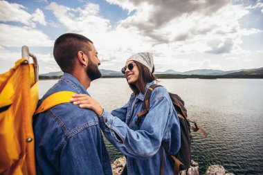 Sırt çantalı yürüyüşçüler dağ gölünün keyfini çıkarıyorlar.