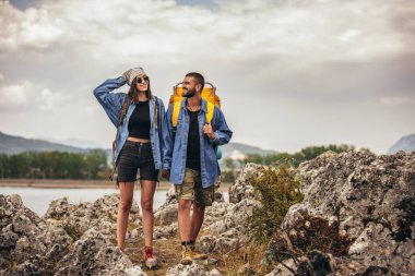 Sırt çantalı yürüyüşçüler dağ gölünün keyfini çıkarıyorlar.