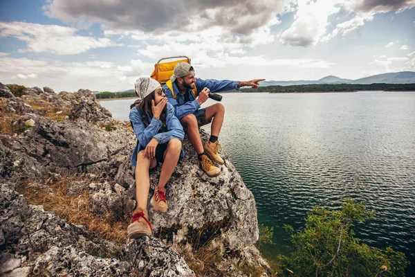 山の湖で楽しむ崖の上に座っているバックパック付きのハイカー — ストック写真