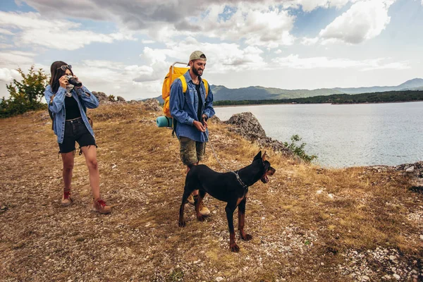 バックパック付きのハイカーや 山の湖で楽しむ犬の散歩 — ストック写真