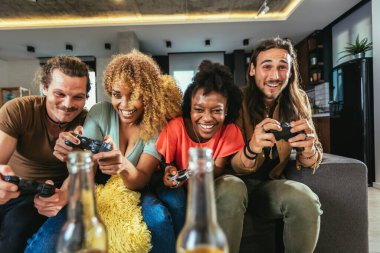 Group of friends playing video games. Happy fellows having fun at home with joysticks playing video games, gesturing and screaming, enjoying time together.