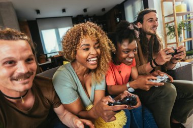 Group of friends playing video games. Happy fellows having fun at home with joysticks playing video games, gesturing and screaming, enjoying time together.