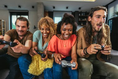 Group of friends playing video games. Happy fellows having fun at home with joysticks playing video games, gesturing and screaming, enjoying time together.