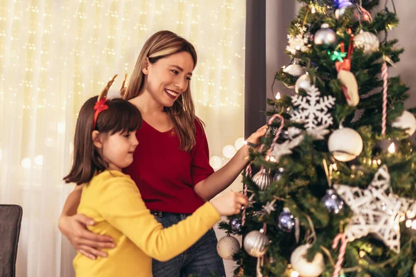 幸せな母と幼い娘が自宅のクリスマス ツリーを飾る — ストック写真