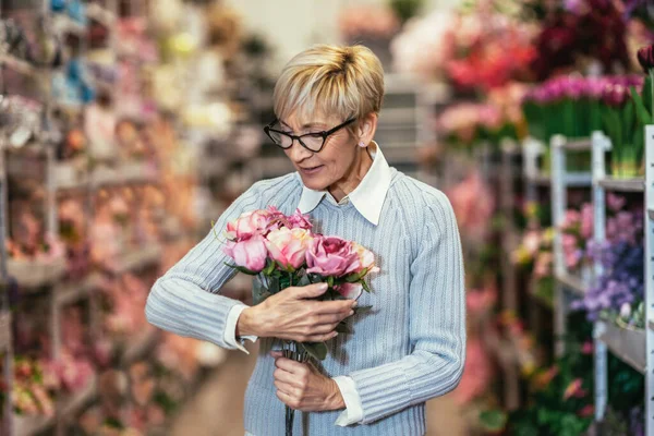 おばあちゃんは笑って花屋で花束を手に — ストック写真