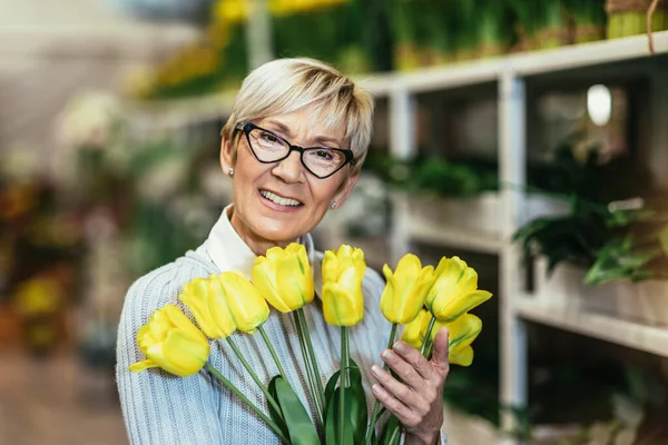 Starsza Pani Uśmiecha Się Trzymając Bukiet Kwiatów Ręku Kwiaciarni — Zdjęcie stockowe