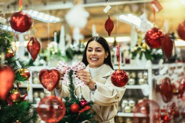 Dekoratif eşya dükkanında Noel süsleri seçen genç bir kadın. Kız Noel süsü alıyor..