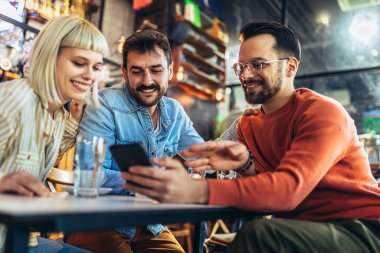 Genç arkadaşlar kafede otururken akıllı telefonlara bakarlar.. 