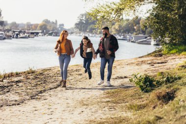 Ebeveynler ve oğulları nehir kenarında yürüyor kırsalda tatil yapıyorlar.