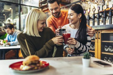 Gülümseyen genç arkadaşlar barda el yapımı bira içiyorlar.