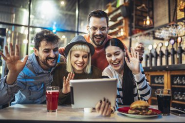 Kafede otururken dijital tablete bakan genç arkadaşlar. 