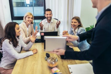 Office colleagues  during meeting in conference room make video call. Business meeting with video call with CEO in office. Young man holding digital tablet during video call.