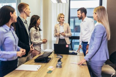 Office colleagues having discussion during meeting in conference room. Group of men and women sitting in conference room and smiling.