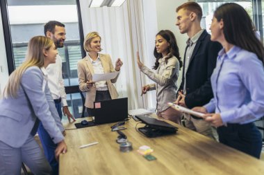 Office colleagues having discussion during meeting in conference room. Group of men and women sitting in conference room and smiling.