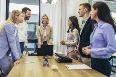 Office colleagues having discussion during meeting in conference room. Group of men and women sitting in conference room and smiling.