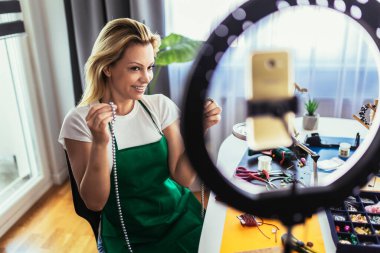 Genç bayan aksesuar tasarımcısı stüdyo atölyesinde el yapımı mücevherler yapıyor ve video kaydediyor. Moda, yaratıcılık ve el yapımı konsept.