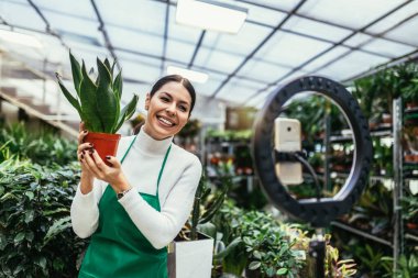 Woman owner on Live Streaming on mobile application by mobile phone for sell flower at flower shop