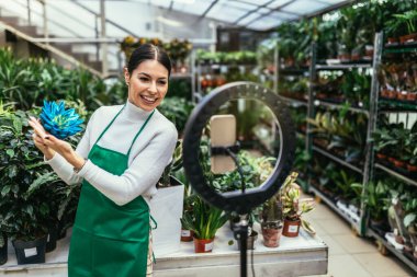Woman owner on Live Streaming on mobile application by mobile phone for sell flower at flower shop