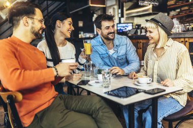 Young people have a great time in a cafe. Friends sitting in a coffee shop, drinking coffee, and having fun together.