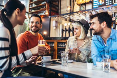 Young people have a great time in a cafe. Friends sitting in a coffee shop, drinking coffee, and having fun together.