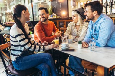 Young people have a great time in a cafe. Friends sitting in a coffee shop, drinking coffee, and having fun together.