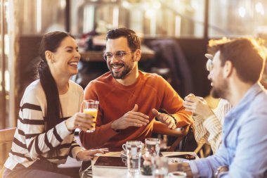 Young people have a great time in a cafe. Friends sitting in a coffee shop, drinking coffee, and having fun together.