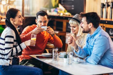 Young people have a great time in a cafe. Friends sitting in a coffee shop, drinking coffee, and having fun together.