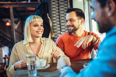 Young people have a great time in a cafe. Friends sitting in a coffee shop, drinking coffee, and having fun together.