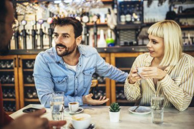 Young people have a great time in a cafe. Friends sitting in a coffee shop, drinking coffee, and having fun together.
