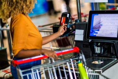 African American Woman with bank card buying food at grocery store or supermarket self-checkout