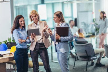 Ofiste konuşan üç iş kadını. Ofiste duran mutlu iş arkadaşları