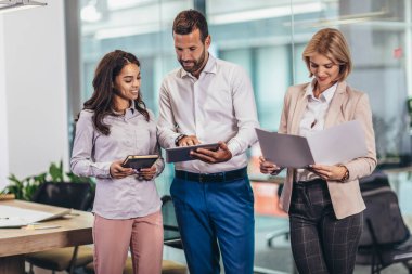 Group of young business people working together while standing in creative office
