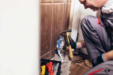 Broken wall tile and during repairing of heated rail. A handyman repairs a pipe in the bathroom.