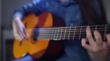 Musician playing on acoustic guitar at home