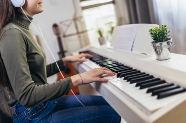 Happy girl is playing piano for her hobby relax time in home living room. Portrait Of Smiling Teenage Girl At Home Playing The Piano