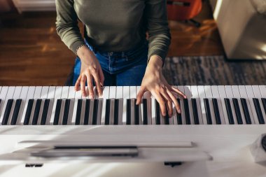 Çocuk evdeki modern elektrikli piyanoda pratik yapıyor. Müzik dersi. Yakın plan. Yüksek açı görünümü.