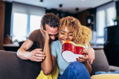 Surprised woman opening a present her boyfriend bought her for their anniversary.