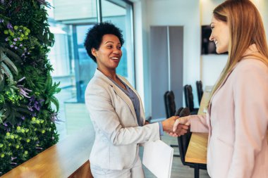 Two business women handshake in the office. Business woman arranges business meeting with company.