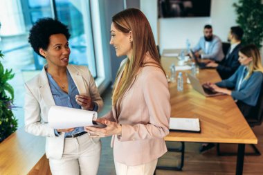 Two business women having a discussion, they're standing in the office.