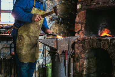 Demirci demircideki erimiş metali elle dövüyor. Havai fişeklerle kıvılcım saçıyor. Yaklaş.