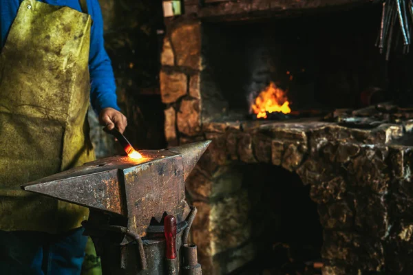 기능공 이손으로 모루에 용융된 금속을 불꽃을 튀기는 폭죽을 끼워서 닫는다 — 스톡 사진