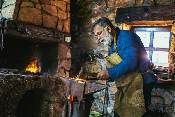 手工锻造用火花烟花的铁匠铺里铁砧上的熔融金属的铁匠 — 图库照片
