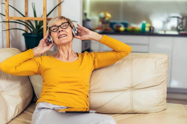 Счастливая Пожилая Женщина Наушниках Улыбается Слушая Музыку Дома — стоковое фото